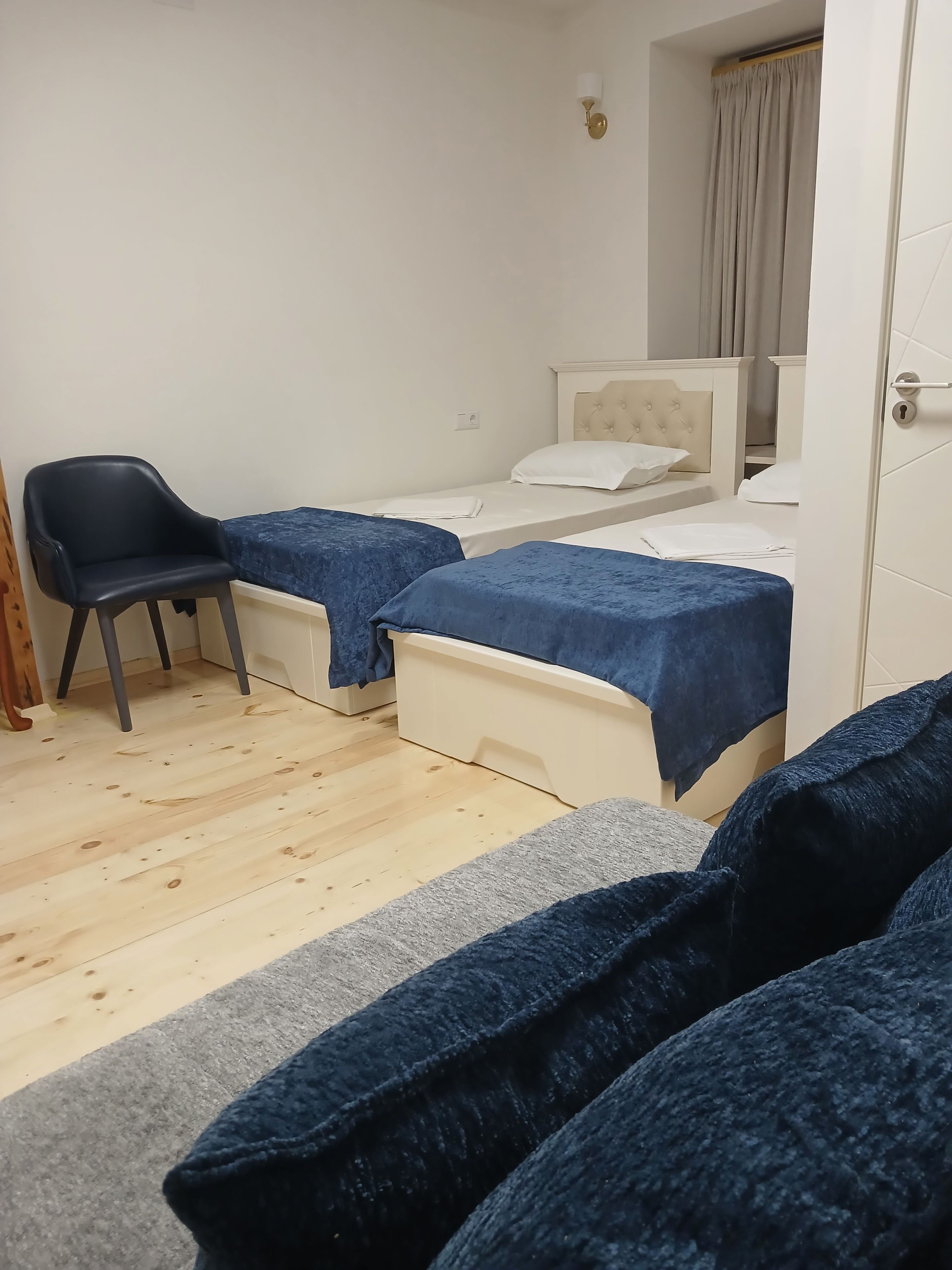 A small room with two beds, a chair, and a door.