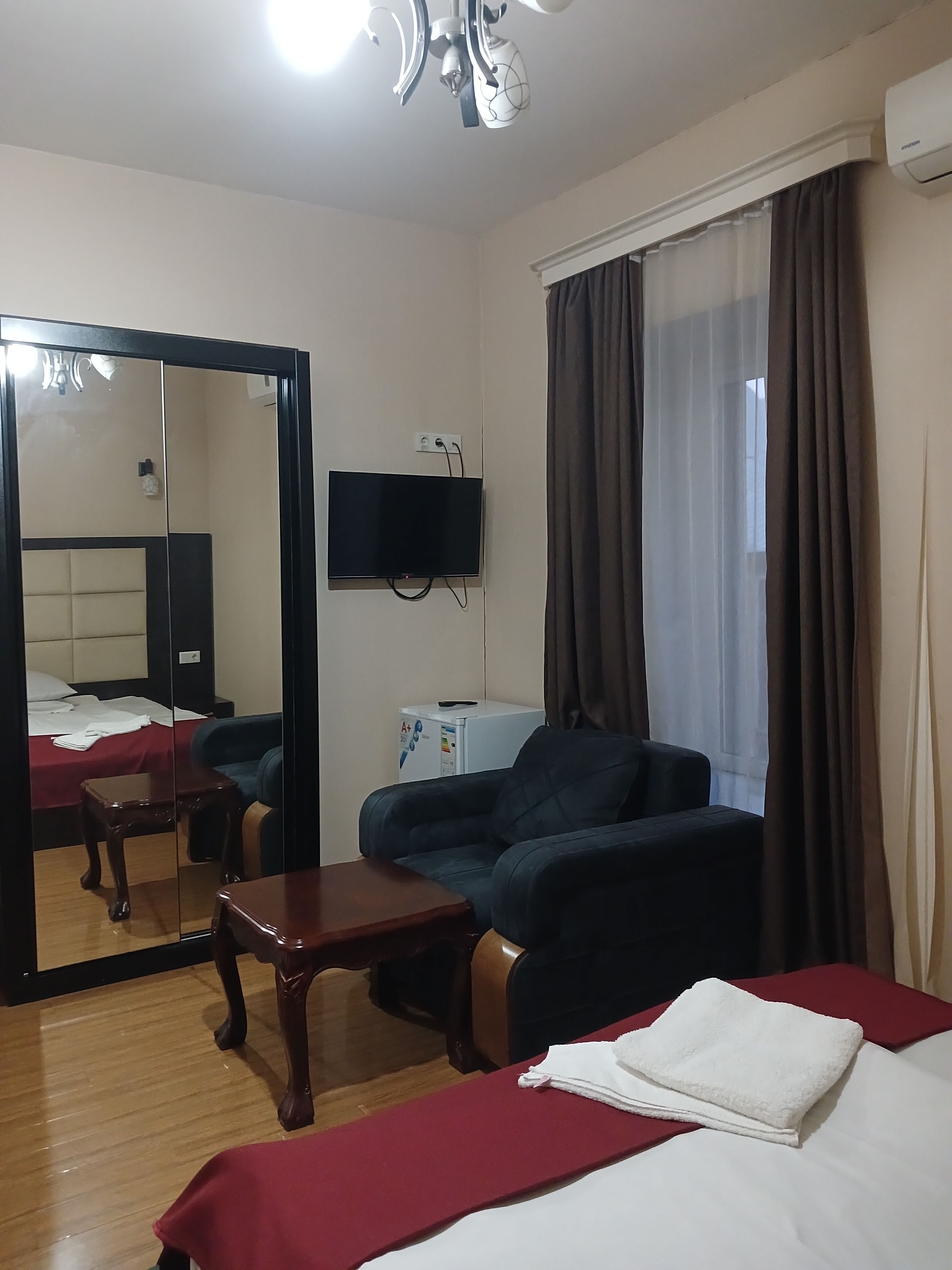 Una habitación de hotel con una cama, un sofá, un televisor, un espejo y una mesita.