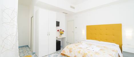 A bedroom with a bed, a wardrobe, a desk, and a chair.