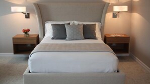 A modern bedroom with a large bed, two bedside tables, and wall-mounted lamps. - Deluxe Queen Room in Minneapolis Boutique Hotel (Minneapolis)