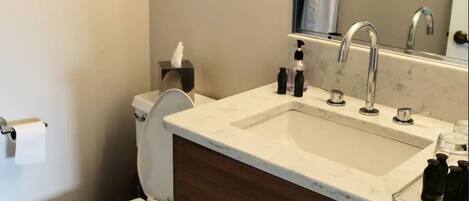A bathroom with a toilet, sink, and mirror.