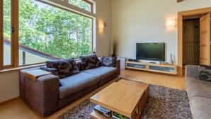 Una sala de estar moderna con un ventanal grande, un sofá, una mesa de centro y un televisor.