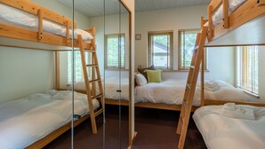 Una habitación con literas, una escalera y un ventanal con persianas.
