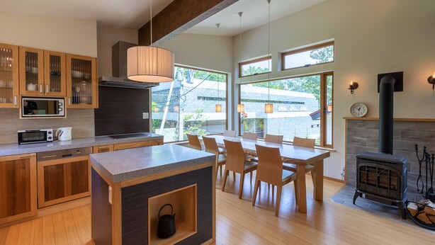 Una cocina moderna con armarios de madera, una isla central y un comedor con sillas.