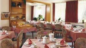 A dining area with tables set for breakfast, featuring tea sets, cups, and plates. - Hartmann (Neuffen)