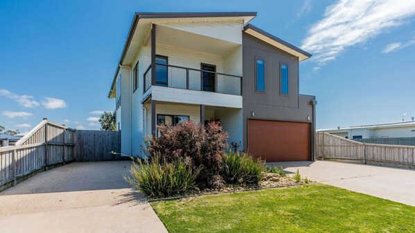 Une maison moderne à deux étages, dotée d’un garage, d’un patio couvert et d’une pelouse bien entretenue.