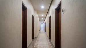 Un pasillo largo y estrecho con puertas de madera a ambos lados y una alfombra estampada.