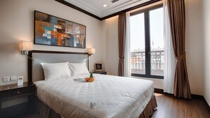 Una camera d'albergo con un letto grande, un quadro appeso al muro e vista sulla città dalla finestra.
