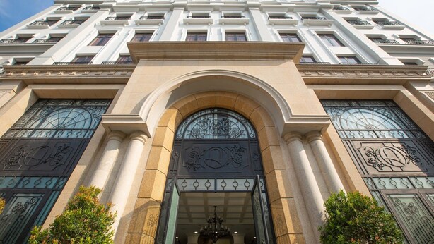 Un edificio a più piani con un ingresso imponente, caratterizzato da ampie porte ad arco e decorazioni in ferro battuto.