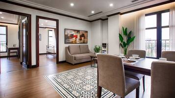 A modern serviced apartment with a dining area, a living room with a sofa, a large window with a view, and a decorative rug.