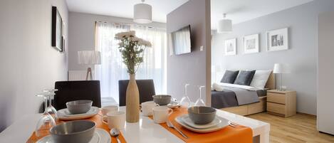A modern hotel room with a dining area, a bed, and a TV.
