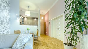 Ein modernes Wohnzimmer mit einer Couch, einem Esstisch und Stühlen. Eine Topfpflanze und eine Heizung sind an der Wand zu sehen.