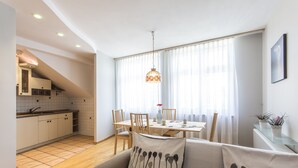 A modern kitchen with white cabinets and a dining area with a table and chairs. - Apartament Amber Krakow (Kraków)