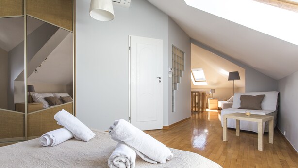 A bedroom with a large bed, a wooden floor, a white door, a sofa, and a small table. - Apartament Amber Krakow (Kraków)