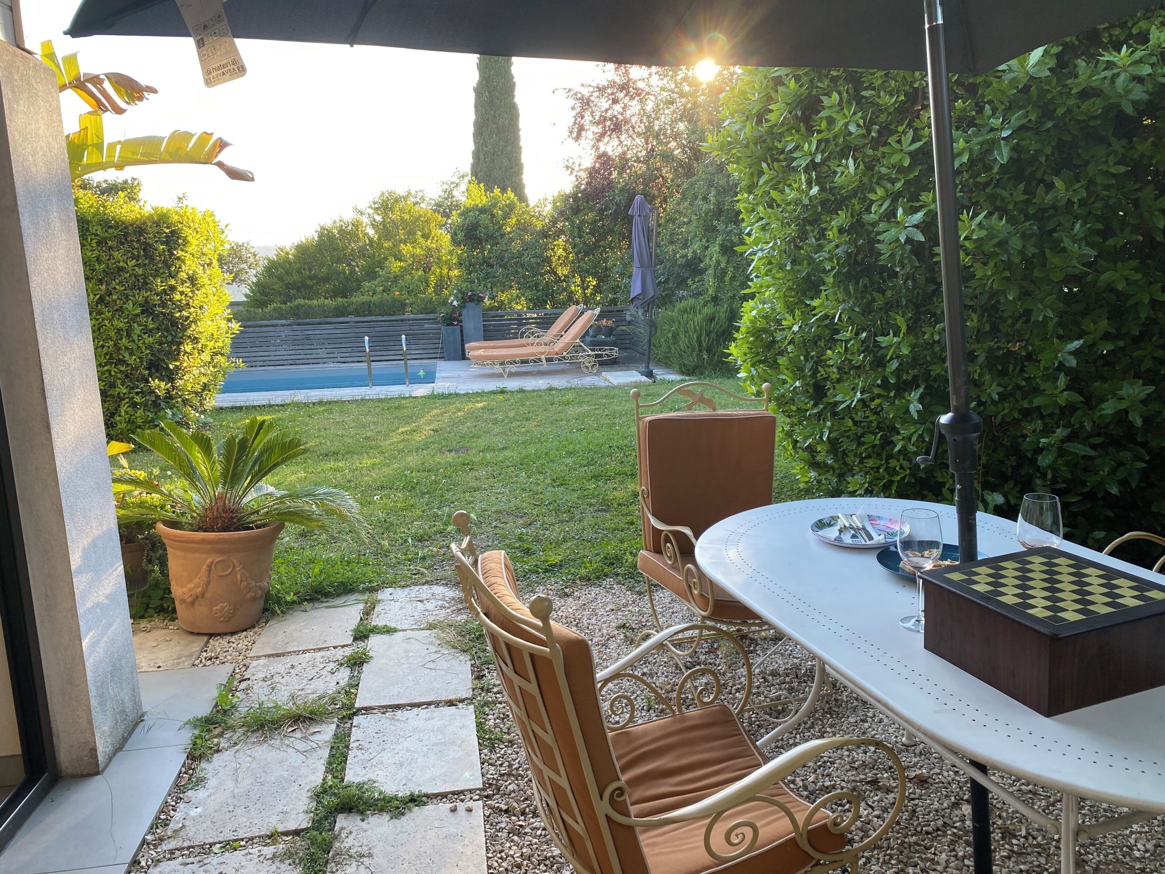 Een terras buiten met een tafel, stoelen en een schaakbord.