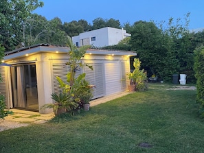 Una casa moderna amb un porxo cobert, un garatge amb portes corredisses i un jardí ben cuidat.