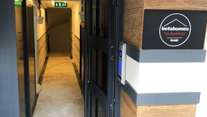 A hotel corridor with a wooden wall, a sign for 'betahomes boutique hotel', and an exit sign. - Beta Homes Boutique Hotel (Izmir)