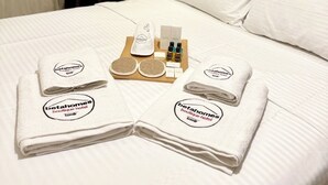 A neatly made bed with white linens, a set of towels, and toiletries on a tray. - Beta Homes Boutique Hotel (Izmir)