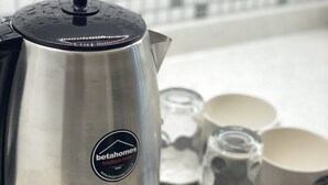 A stainless steel coffee maker with a black lid and a logo, a tray with coffee cups, a packet of Nescafe coffee, and a packet of Turkish coffee. - Beta Homes Boutique Hotel (Izmir)