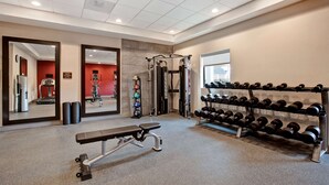 A gym with a bench, weight racks, and exercise machines. - Home2 Suites by Hilton Charlotte Northlake (Charlotte)