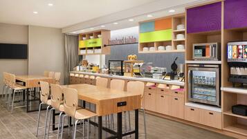 Un espace cuisine moderne comprenant une table et des chaises, un coin café et un réfrigérateur.