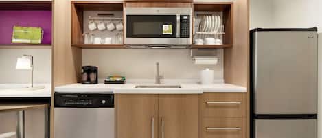 A compact kitchen with a built-in microwave, a refrigerator, and a dishwasher.