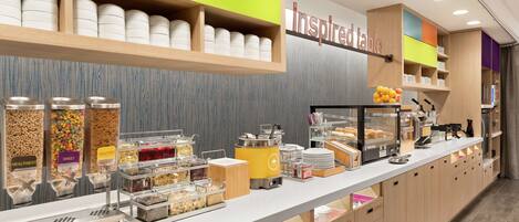 A breakfast buffet with labeled containers of food, a coffee machine, and a sign that says "inspired table".