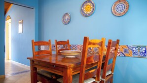 A dining area with a wooden table and chairs, blue walls, and decorative plates on the wall. - Solemar Sicilia - Casa Enza (Santa Flavia)