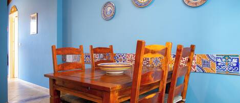 Un coin repas avec une table et des chaises en bois, des murs bleus et des assiettes décoratives accrochées au mur.
