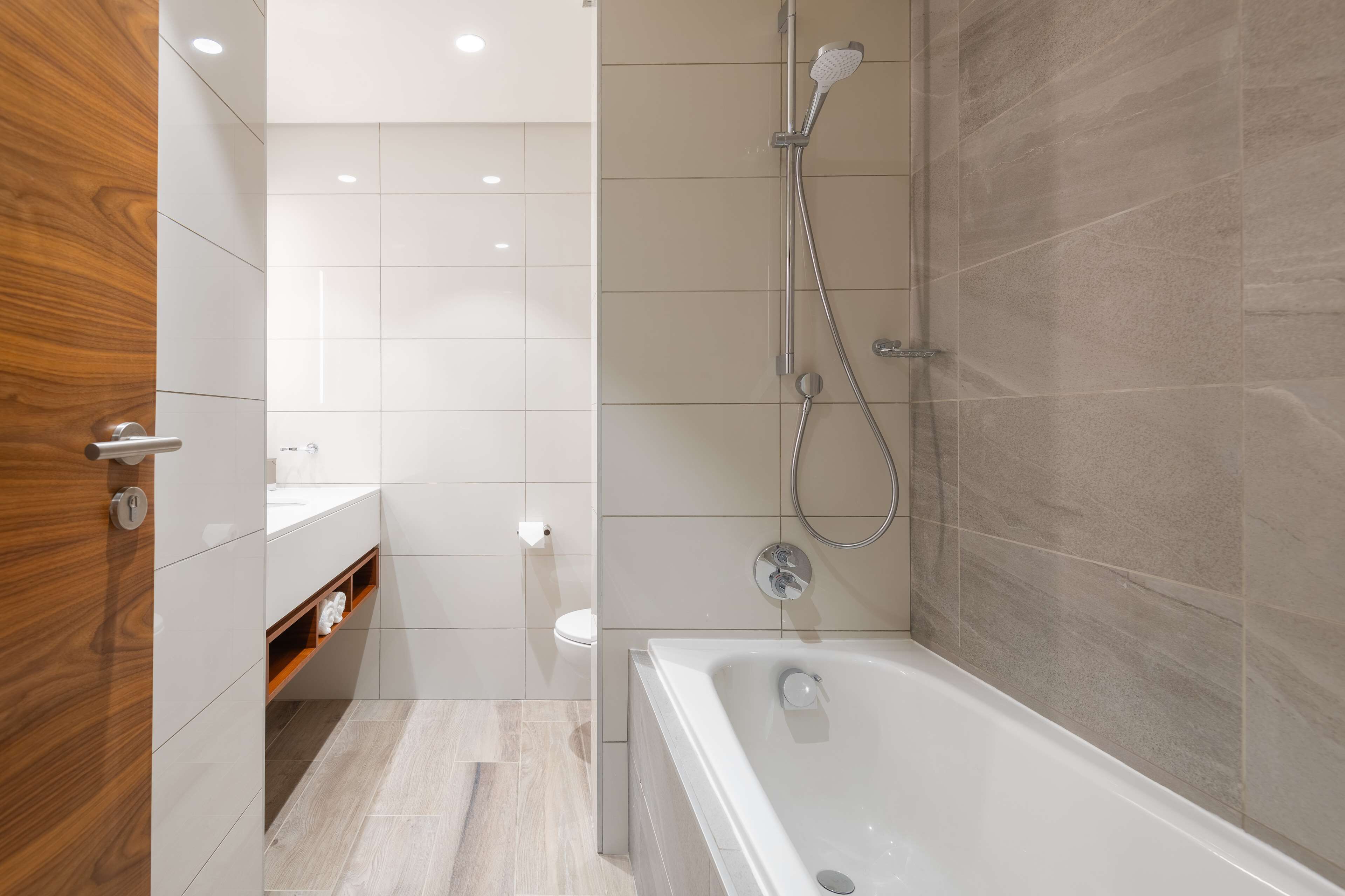A modern bathroom with a bathtub, shower, and toilet.