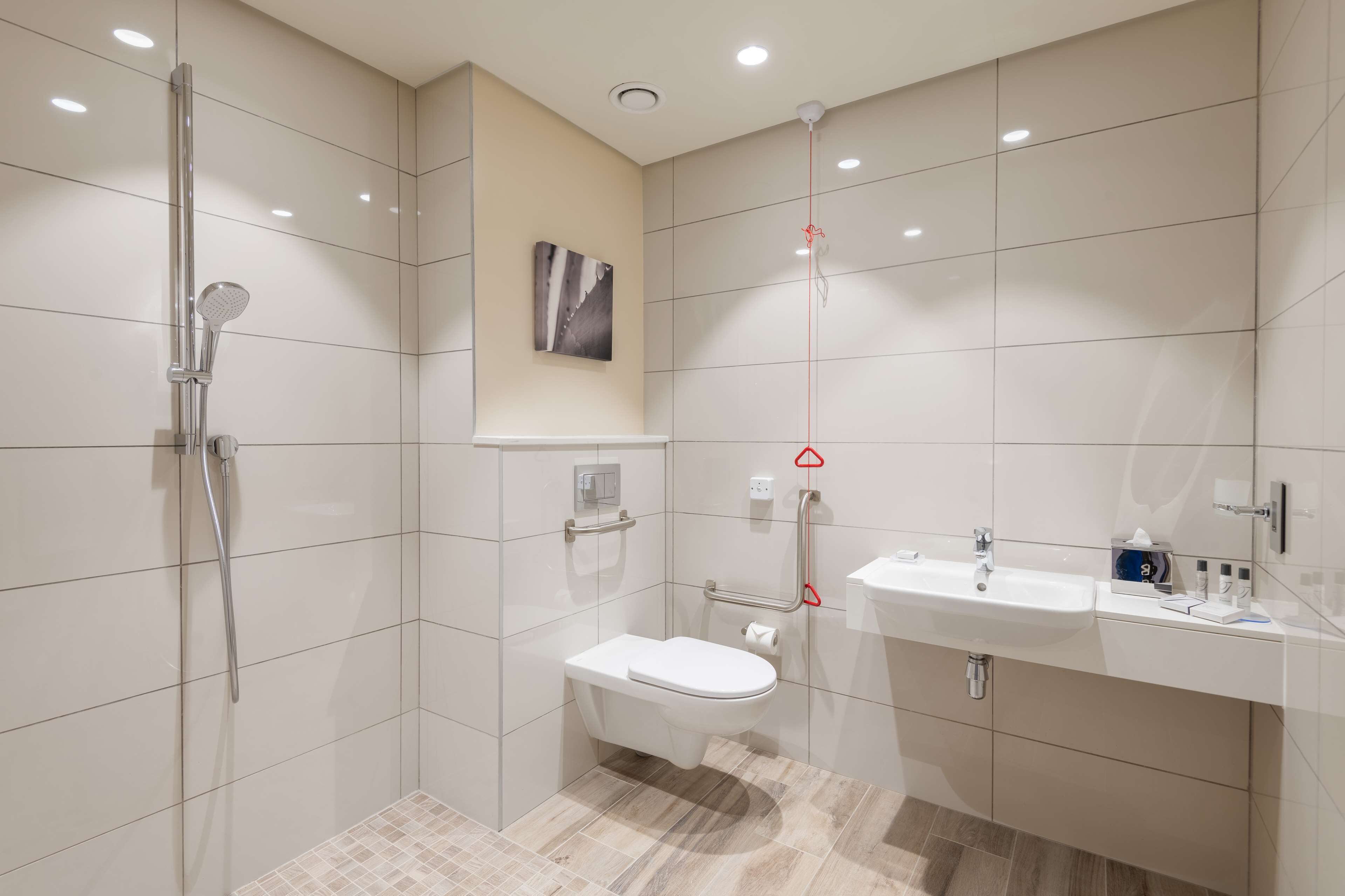 A modern bathroom with a shower, toilet, and sink.