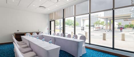 A conference room with a long table, chairs, and a view of the outside.