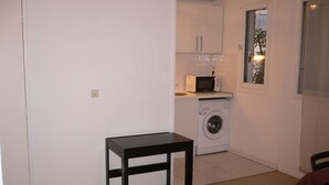 Une petite buanderie équipée d’un lave-linge, d’un four à micro-ondes et d’une table.