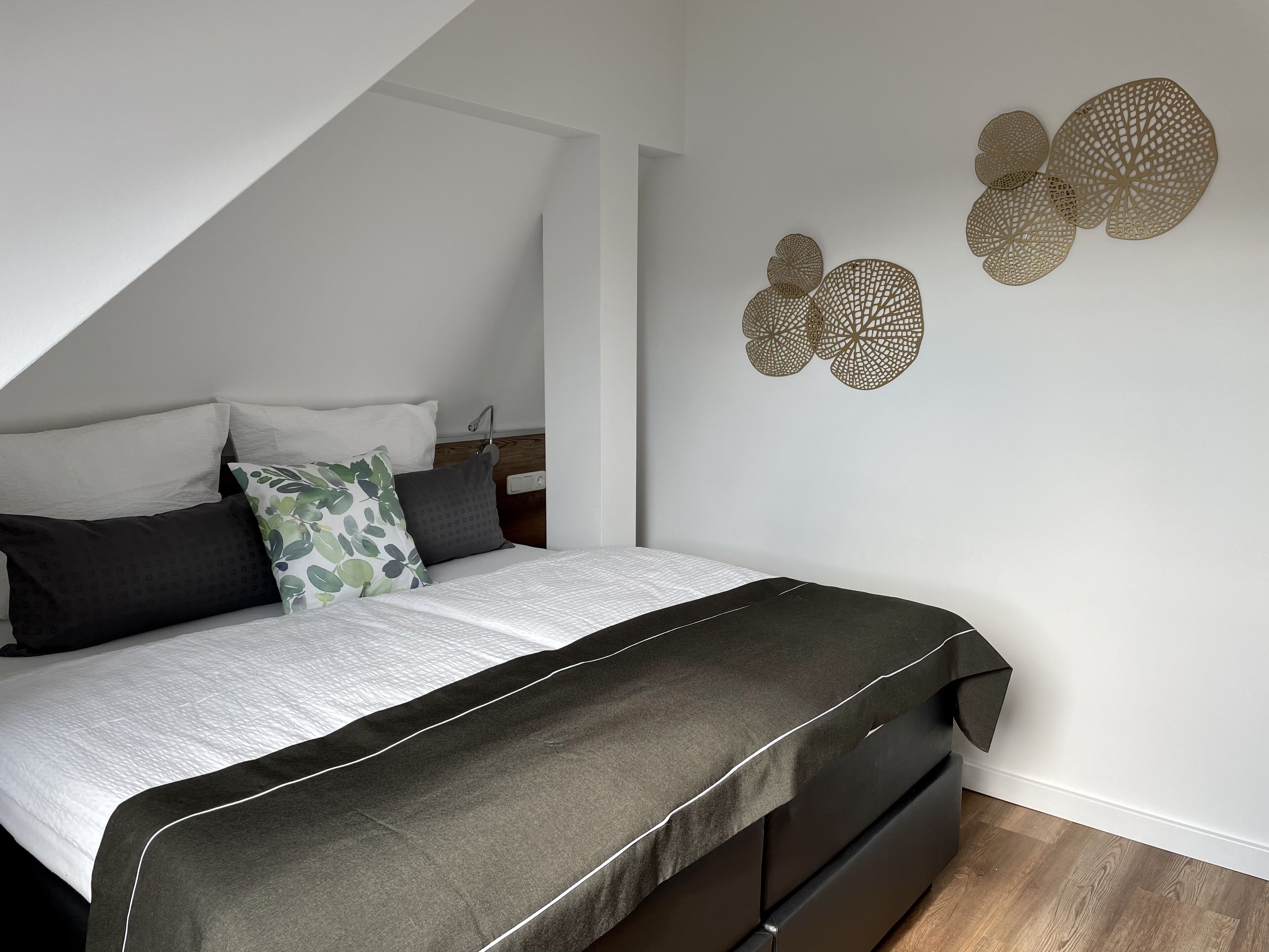 Une chambre à coucher moderne avec un lit, des oreillers et des œuvres d’art décoratives au mur.
