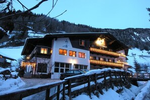 A two-story building with a balcony, surrounded by snow-covered landscape and trees. - Garni Wildbach (Selva di Val Gardena)