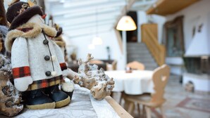 A rustic interior with a wooden table displaying a decorative figure and a piece of driftwood. - Garni Wildbach (Selva di Val Gardena)