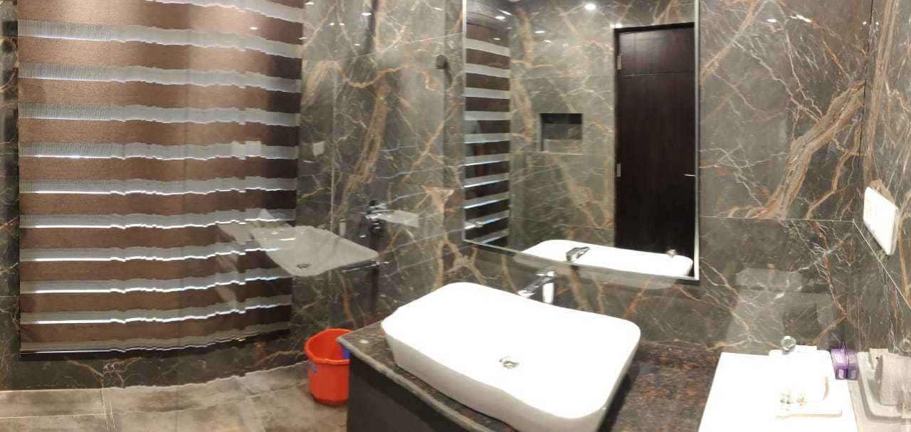 A bathroom with a large mirror, a white sink, and a shower area.