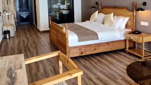 A bedroom with a wooden bed, a nightstand, a bedside table, and a ceiling fan. - Parwati Retreat (Ranikhet)