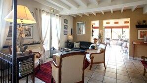 A spacious living room with a fireplace, a dining area, and a view of the outdoors. - Hotel Coté Rivage (Badefols-sur-Dordogne)