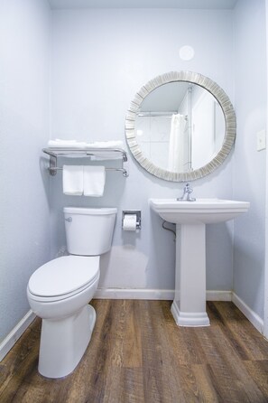 Un baño con inodoro, lavamanos y un espejo redondo.