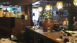 Zona de bar con mostradores de madera, faroles colgantes y vistas al exterior a través de una ventana.