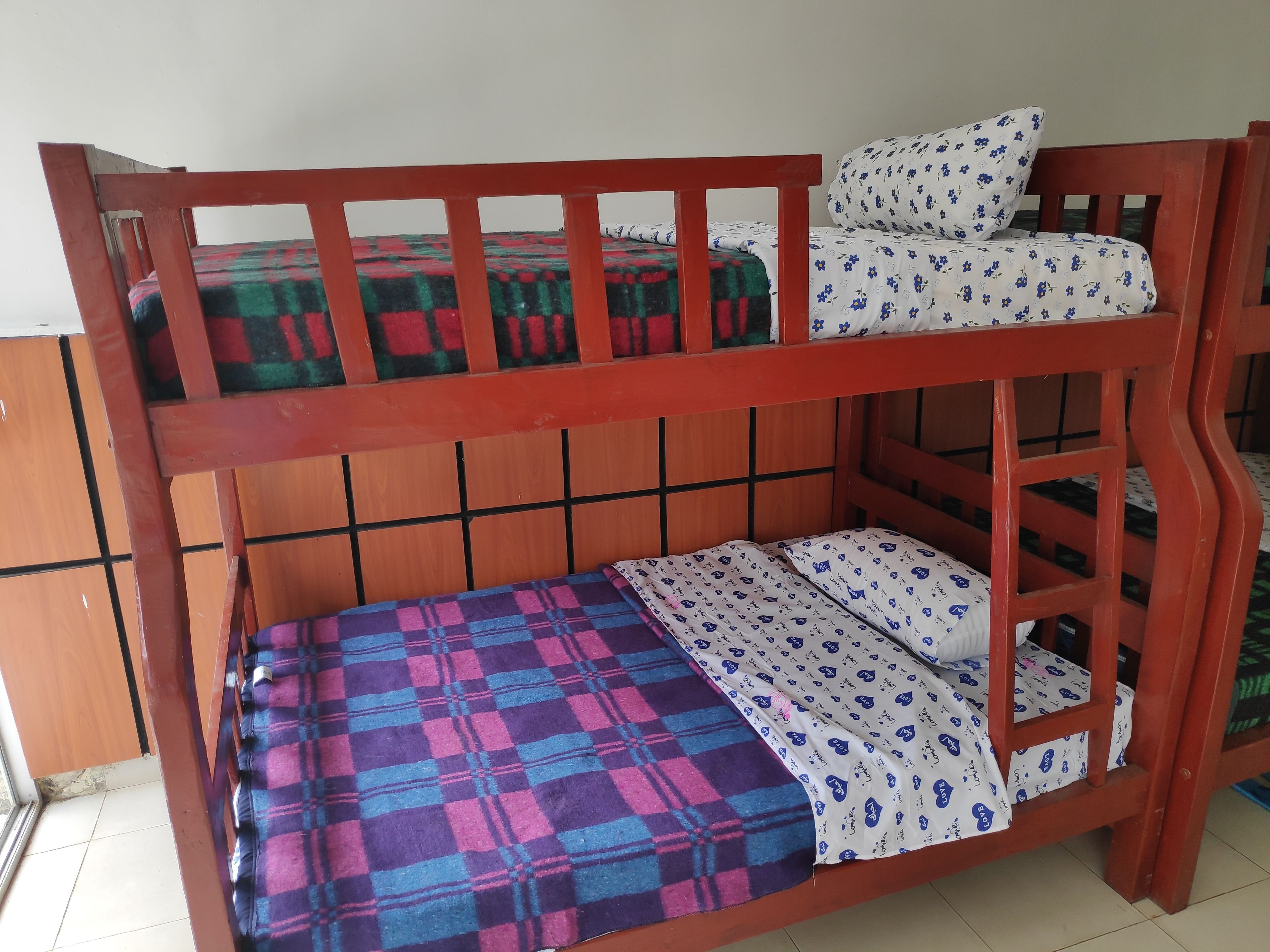 A bunk bed with a checkered blanket and patterned sheets.