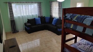 A room with a sectional sofa, a bunk bed, and a small table. - Casa Tulia Nakuru (Nakuru)
