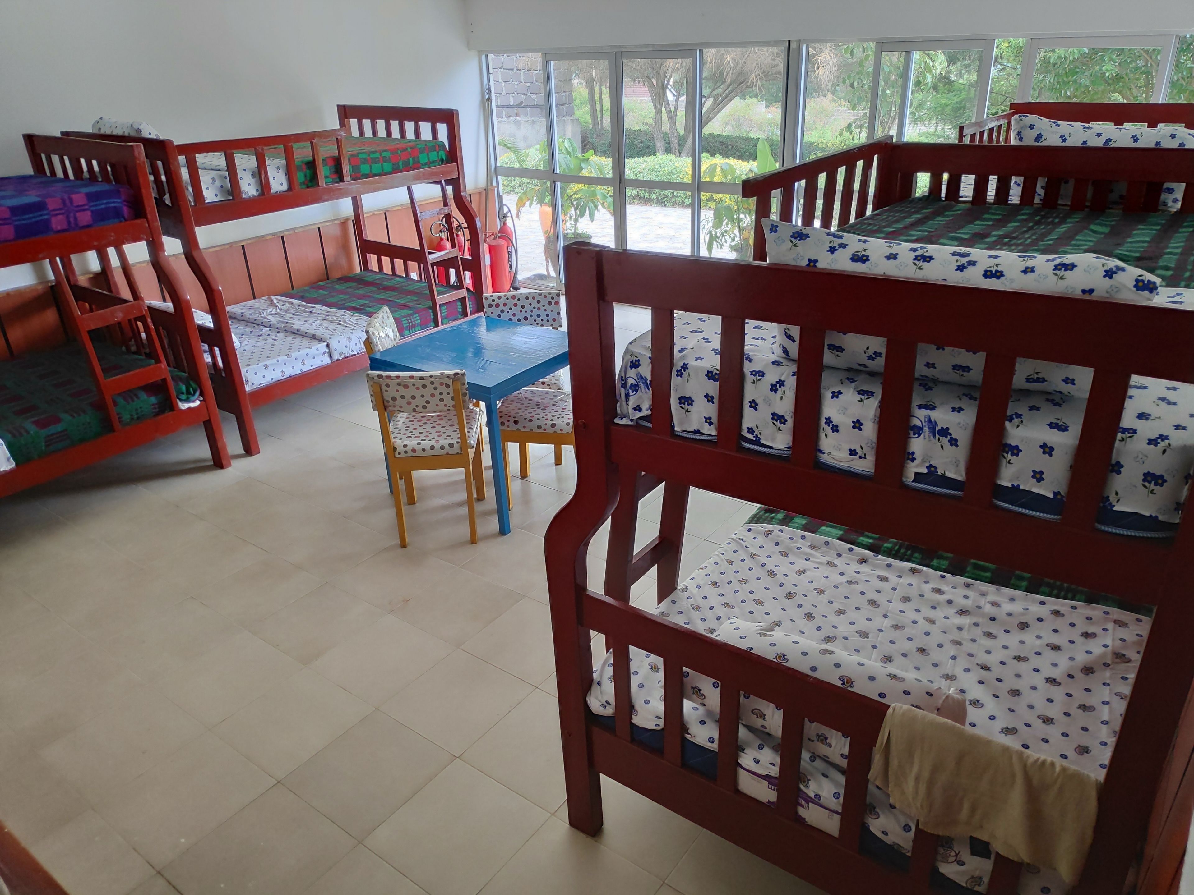 A dormitory room with bunk beds, a dining table, and chairs.