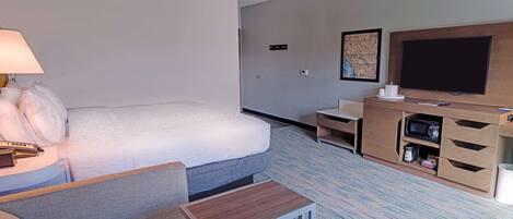 A hotel room with a bed, a desk, a television, and a microwave.