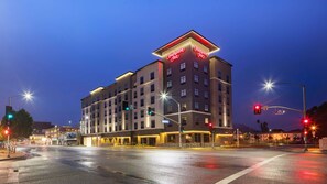 A Hampton Inn hotel with a modern design, multiple floors, and a prominent neon sign.