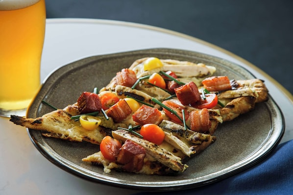 A plate of grilled chicken with bacon and cherry tomatoes.