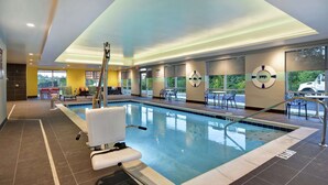 An indoor swimming pool with a lifeguard chair, a pool ladder, and a view of the outside through large windows. - Tru By Hilton Cincinnati Airport South Florence (Florence)