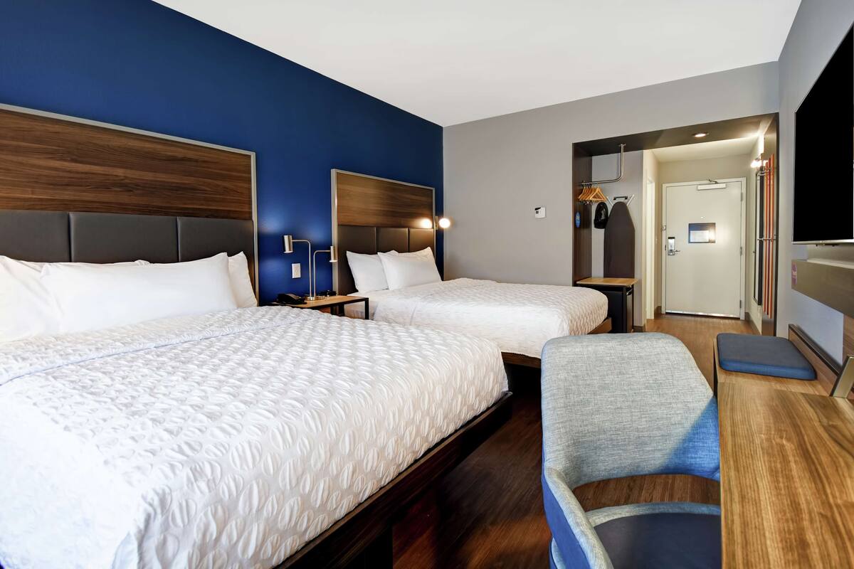 Una habitación de hotel con dos camas, un escritorio y una silla.