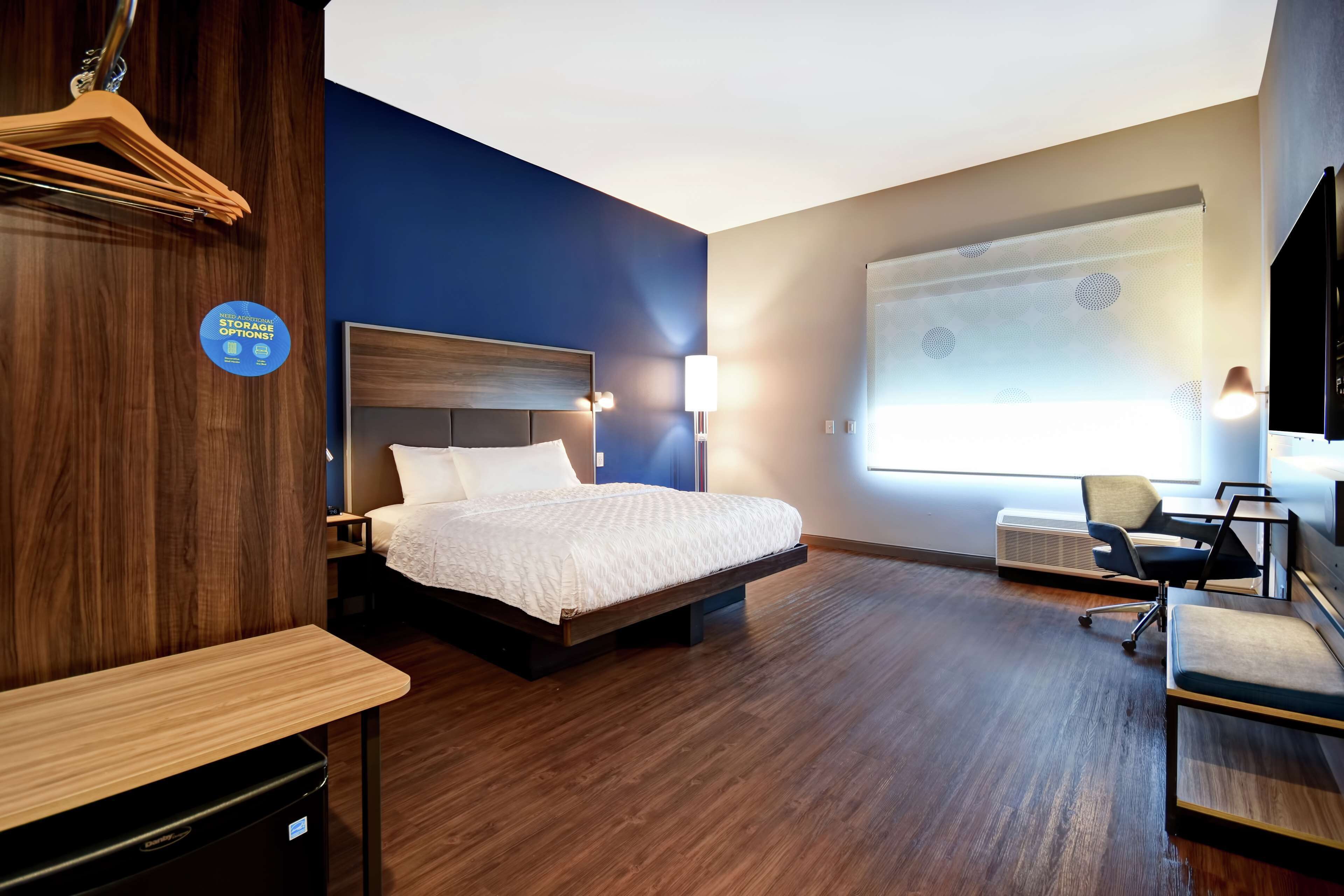 Une chambre d’hôtel équipée d’un lit, d’un bureau, d’une chaise et d’un écran de projection mural.